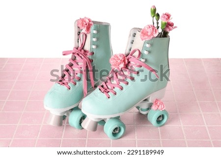 Roller skates with spring flowers on table against white background