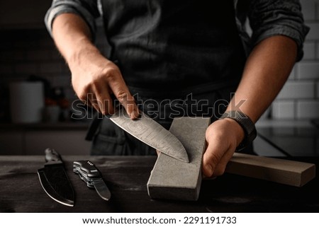 Man sharpening a knife with sharpen stone tool. Master sharpening knife on a grindstone Royalty-Free Stock Photo #2291191733