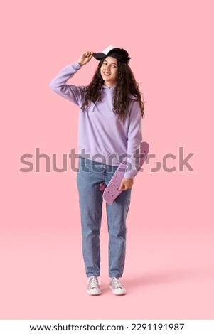 Teenage girl in cap with skateboard on pink background