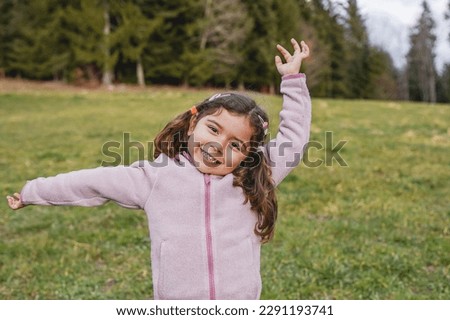 Happy female child posing in front of camera - Little girl smiling on camera during trekking day at mountain forest - Childhood concept