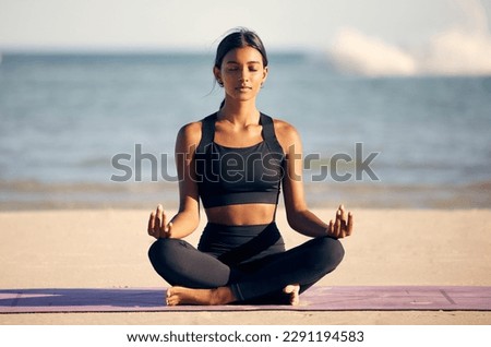 On the search for inner peace. Full length shot of an attractive young woman meditating on the beach. Royalty-Free Stock Photo #2291194583