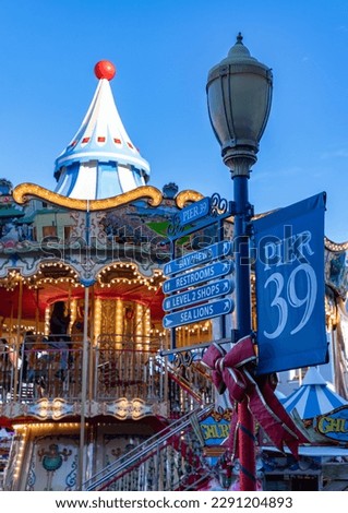 A picture of the signs of Pier 39 next to its iconic colorful carousel. Royalty-Free Stock Photo #2291204893