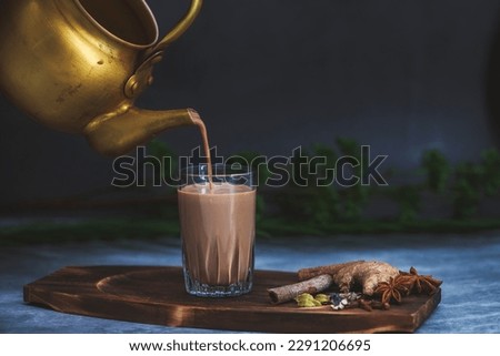 Indian masala chai tea. Masala chai spiced tea with milk and spices or karak chai or cutting chai. Tea being poured into glasses from a kettle. Restaurants and bar concept. Royalty-Free Stock Photo #2291206695