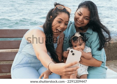 Mother and sister taking a selfie with her baby