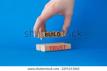 Build trust symbol. Wooden blocks with words Build trust. Beautiful blue background. Businessman hand. Business and Build trust concept. Copy space.