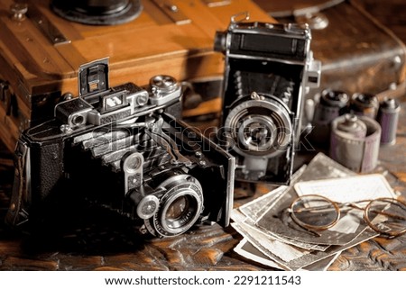 The camera is old, on an old background, in a composition with accessories for photography.
