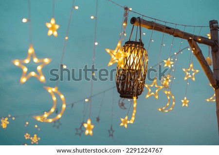 Lighting decor elements at a party outdoors. Cozy lights lanterns and light garland background. Royalty-Free Stock Photo #2291224767