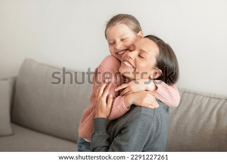 Cheerful happy cute european teen girl hugging millennial mom, have fun, enjoy spare time in living room interior, free space. Love, support, care and relationships at home Royalty-Free Stock Photo #2291227261