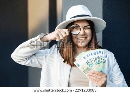 Attractive woman with cash in her hands and magnifying glass.
