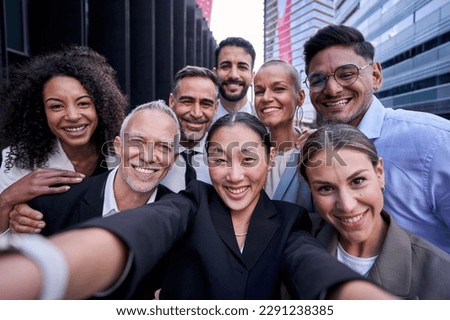 Happy multicultural group of male and female business people taking a selfie together outdoors at workplace. Chinese businesswoman making a photo with her work colleagues. Royalty-Free Stock Photo #2291238385