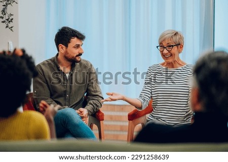 Diverse group of patients gathered in circle at psychologist office discussing self problems while listening others. Getting psychological support. Focus on a smiling senior woman. Copy space. Royalty-Free Stock Photo #2291258639