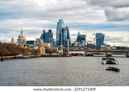 A panoramic view of River Thames with St. Paul's Cathedral, The Cheese Grater and other iconic buildings in the background, captured on a clear day.
