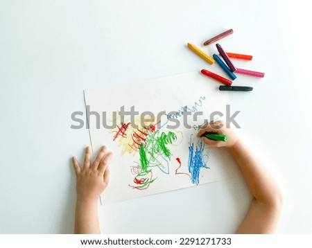 small child draws with pastel crayons on white table. fathers day