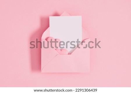 Open pink envelope with paper card and heart on pastel pink table background. Birthday, Wedding, Mother's Day, Valentine's day, Women's Day. Flat lay, top view, copy space Royalty-Free Stock Photo #2291306439