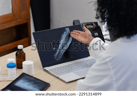 Biracial female doctor using laptop with radiograph on screen at doctor's office. Hospital, medicine, healthcare and communication.