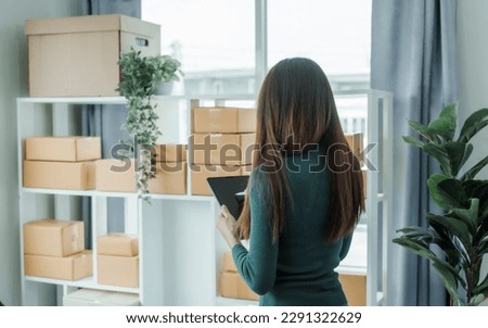 Young pretty Asian female influencer small businesses SME owners female entrepreneurs working on receipt box and check online orders, sitting on sofa of home online business.