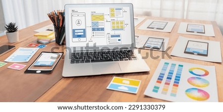 Digital and paper wireframe designs for web or mobile app UI UX display on laptop computer screen. Panoramic shot of developer workspace for brainstorming and design application framework. Scrutinize Royalty-Free Stock Photo #2291330379