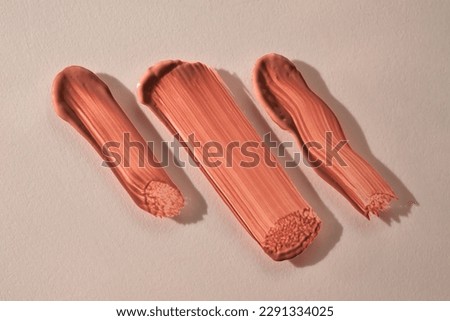 Three strokes of lip gloss on a beige background. Royalty-Free Stock Photo #2291334025