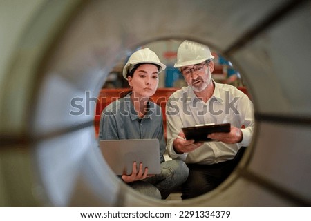 partner woman engineer assistant in helmet inspection check heavy machine construction installation in industrial metal roof roll sheet factory with colleague manager. partnership operation factory