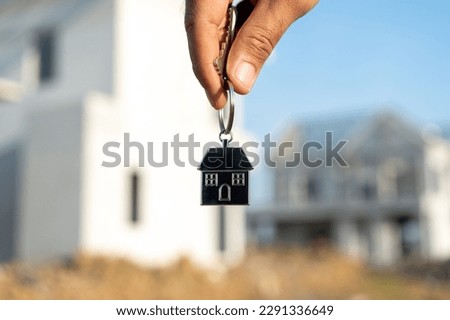 Close up male hand holding house key with sunlight. Real estate agent at construction site. New home purchase sales or rent. Choose Planning to buy property Royalty-Free Stock Photo #2291336649