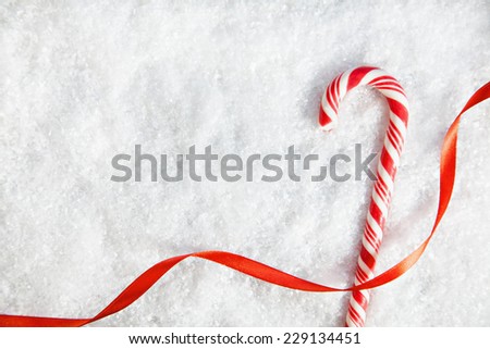 Candy Cane And Ribbon On Snowy Background. Copy Space