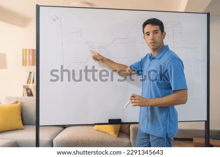 Man pointing a graph during explanation with a board in a home office Royalty-Free Stock Photo #2291345643