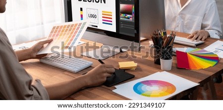 Graphic designer work on computer laptop and with graphic drawing pen while brainstorming unique design with professional graphic team in modern digital studio workplace. Panorama shot. Scrutinize Royalty-Free Stock Photo #2291349107
