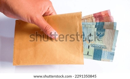 Hand holding money in indonesian rupiah after get THR Tunjangan Hari Raya which is Eid Mubarak Bonuses for Moslems employee. THR.