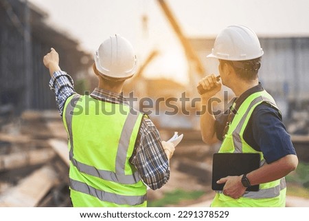 A Team of Civil Engineers and Architects wearing Safety gear Inspect the Construction Site of a High Concrete Bridge at a Highway construction site. Royalty-Free Stock Photo #2291378529
