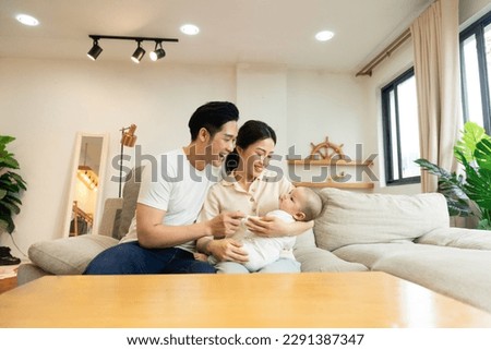 Smiling mother and father holding newborn son at home Royalty-Free Stock Photo #2291387347