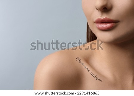 Affirmation. Woman with tattooed phrase You Are Unique on collarbone against light grey background, closeup. Space for text Royalty-Free Stock Photo #2291416865