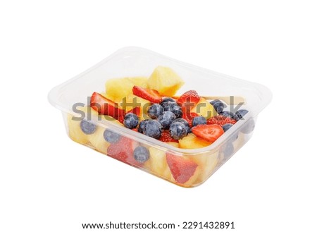 Fruit salad with pineapple, strawberries and blueberries in a plastic container on a white background. High quality photo