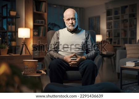 Pensive senior man sitting on the living room alone and relaxing