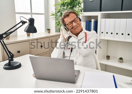 Senior doctor man working on online appointment sleeping tired dreaming and posing with hands together while smiling with closed eyes. 