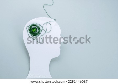 Paper cut out head with of tangled green threads. isolated. flat lay. Anxiety, depression and mental health concept.  Royalty-Free Stock Photo #2291446087