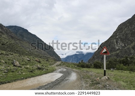 road sign indicating a slope on a wet dirt mountain road after rain. High quality photo
