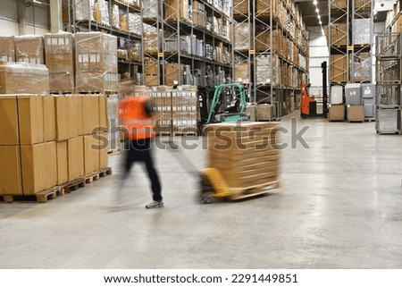 warehouse worker in a forwarding agency - interior with forklift - transport and storage of goods  Royalty-Free Stock Photo #2291449851