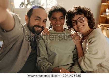 Portrait of happy family with adopted daughter smiling at camera while making selfie portrait Royalty-Free Stock Photo #2291475985
