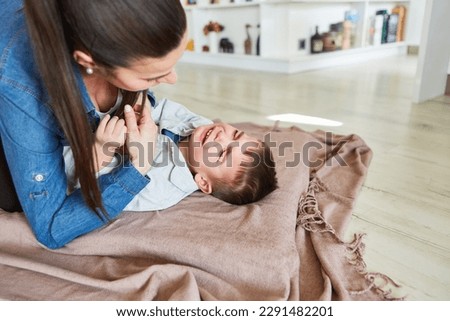 Caring mother taking care of crying son at home in the living room Royalty-Free Stock Photo #2291482201