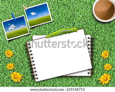 Notepad on an artificial Grass with coffee mug,pictures and clothesline