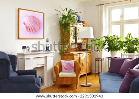 Custom-made home decoration concept: colorful living room with a framed picture of a pink shell, a throw pillow of the same and maritime decorations.