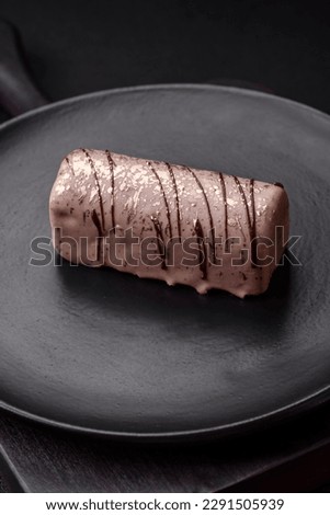 Delicious sweet cheese with syrup covered with chocolate and nuts on a ceramic plate on a dark concrete background