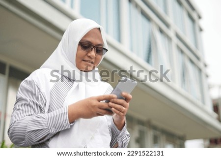 Business woman is online by using cell phone in front of office