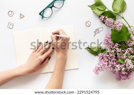 Female spring desktop with lilac flowers bouquet, top view.