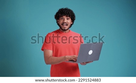 Happy indian man winner wearing earbud winning online raising fist in yes gesture watching game on laptop screaming about goal win celebrating great prize isolated on yellow background. Royalty-Free Stock Photo #2291524883