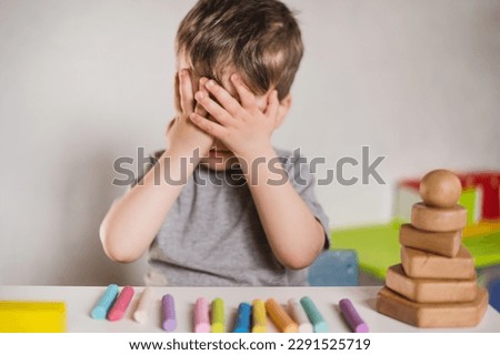Autism Symptoms: Lack of eye contact. Delayed development and social adaptation. Mental health therapy and socialization. Child avoids communication and make eye contact. Eyes closed with hands Royalty-Free Stock Photo #2291525719