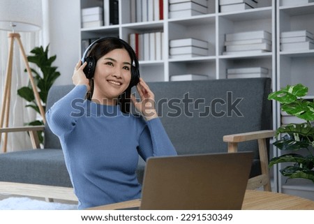 Happy millennial Asian in headphone use laptop take online course training make notes. Smiling young Vietnamese female student in earphones study on computer from home. Distant education concept