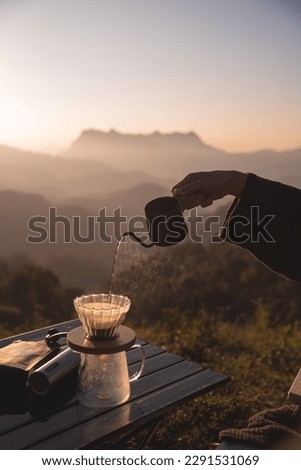 Hand pouring Hot water during brewing arabica coffee by Vintage coffee drip in the morning with mountain background