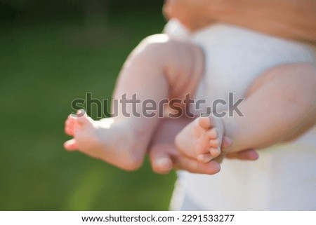 Man in white clothes holding little baby outdoors at sunset light. Fatherhood concept