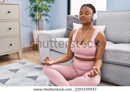 African american woman listening to music doing yoga exercise at home